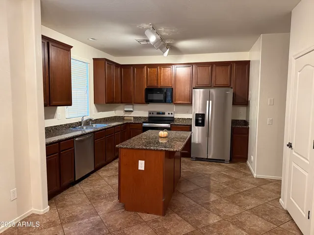 a kitchen with stainless steel appliances granite countertop a refrigerator stove and sink