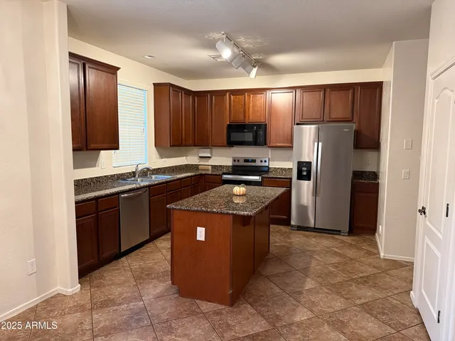 a kitchen with stainless steel appliances granite countertop a refrigerator a stove a sink a microwave and island