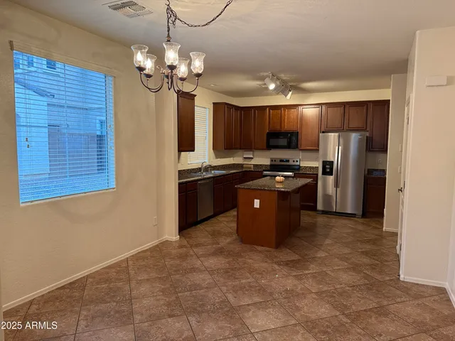 a kitchen with stainless steel appliances granite countertop a stove a refrigerator a sink a microwave and island