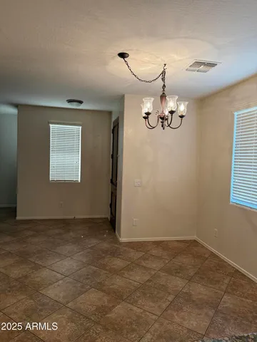 an empty room with a chandelier fan and windows