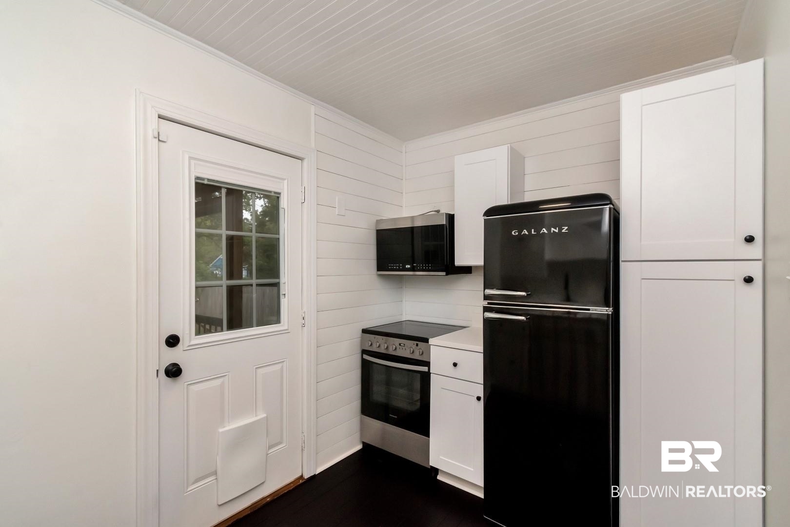 208 Morgan Avenue Mobile, AL 36606 - Photo 11 of 27 Kitchen with appliances with stainless steel finishes, wooden walls, and white cabinets