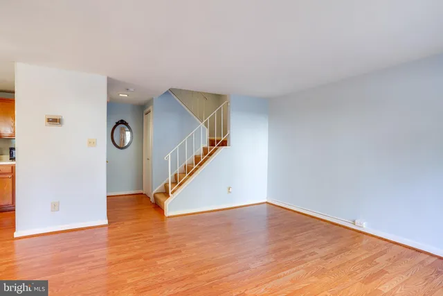 a view of a livingroom with wooden floor and a kitchen space