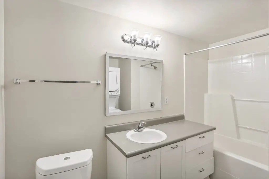 201 Yesler Way Seattle, WA 98104 - Photo 19 of 21 a bathroom with a toilet a sink a mirror a shower a vanity and mirror