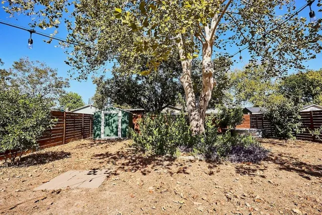 a view of backyard with wooden fence and large trees