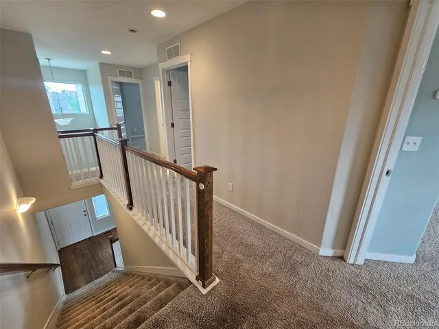 a view of a hallway with wooden floor and staircase