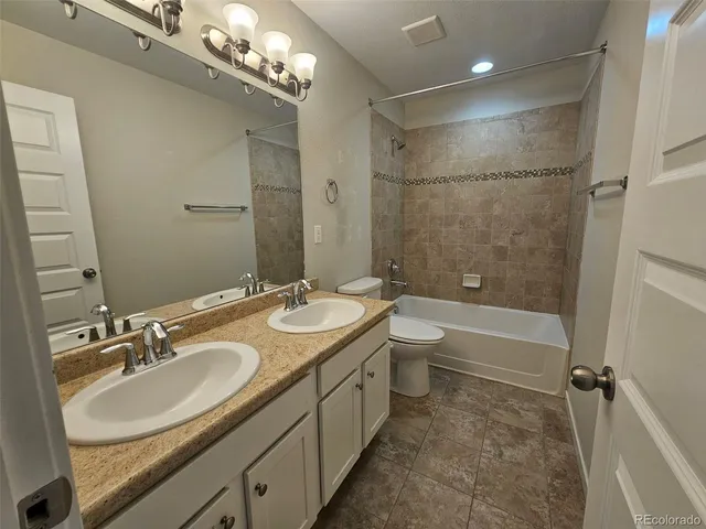 a bathroom with a double vanity sink toilet mirror and bathtub