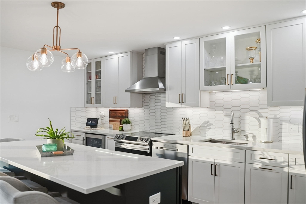 191 Court Road, Unit 3 Winthrop, MA 02152 - Photo 2 of 23 a kitchen with stainless steel appliances kitchen island granite countertop a table chairs in it and wooden floors