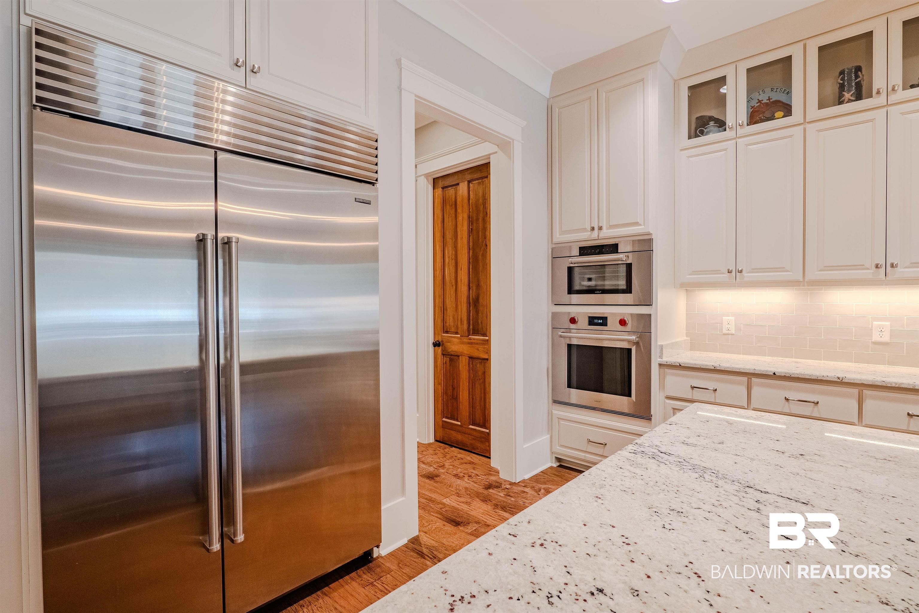 708 Manning Place Fairhope, AL 36532 - Photo 12 of 58 Kitchen featuring tasteful backsplash, white cabinets, light stone counters, stainless steel appliances, and light wood-type flooring