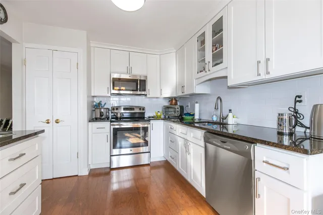 a kitchen with granite countertop white cabinets and stainless steel appliances