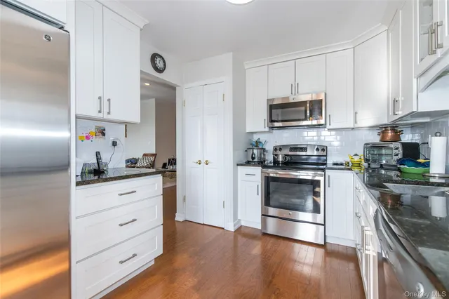 a kitchen with granite countertop white cabinets and stainless steel appliances