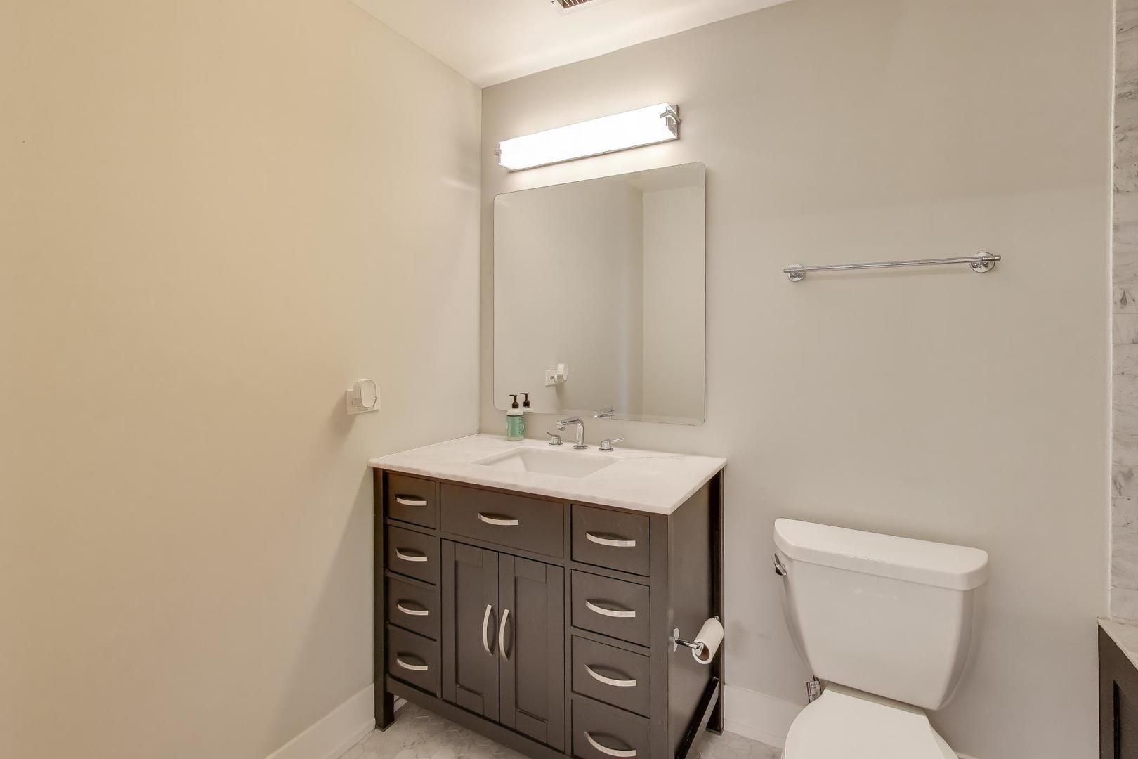 1301 West Madison Street, Unit 315 Chicago, IL 60607 - Photo 17 of 27 a bathroom with a toilet a sink and mirror