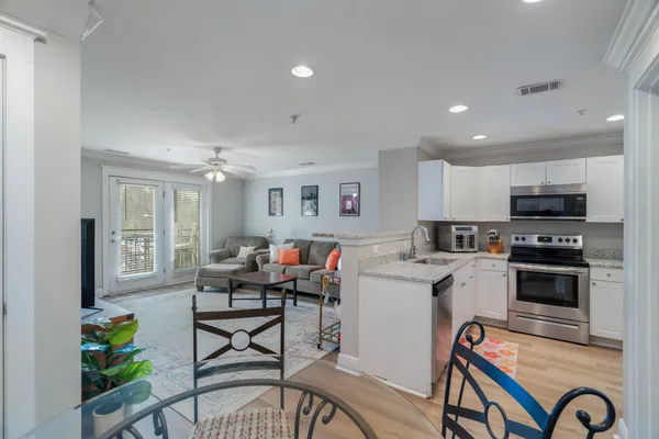 a living room with stainless steel appliances a dining table chairs stove and kitchen view
