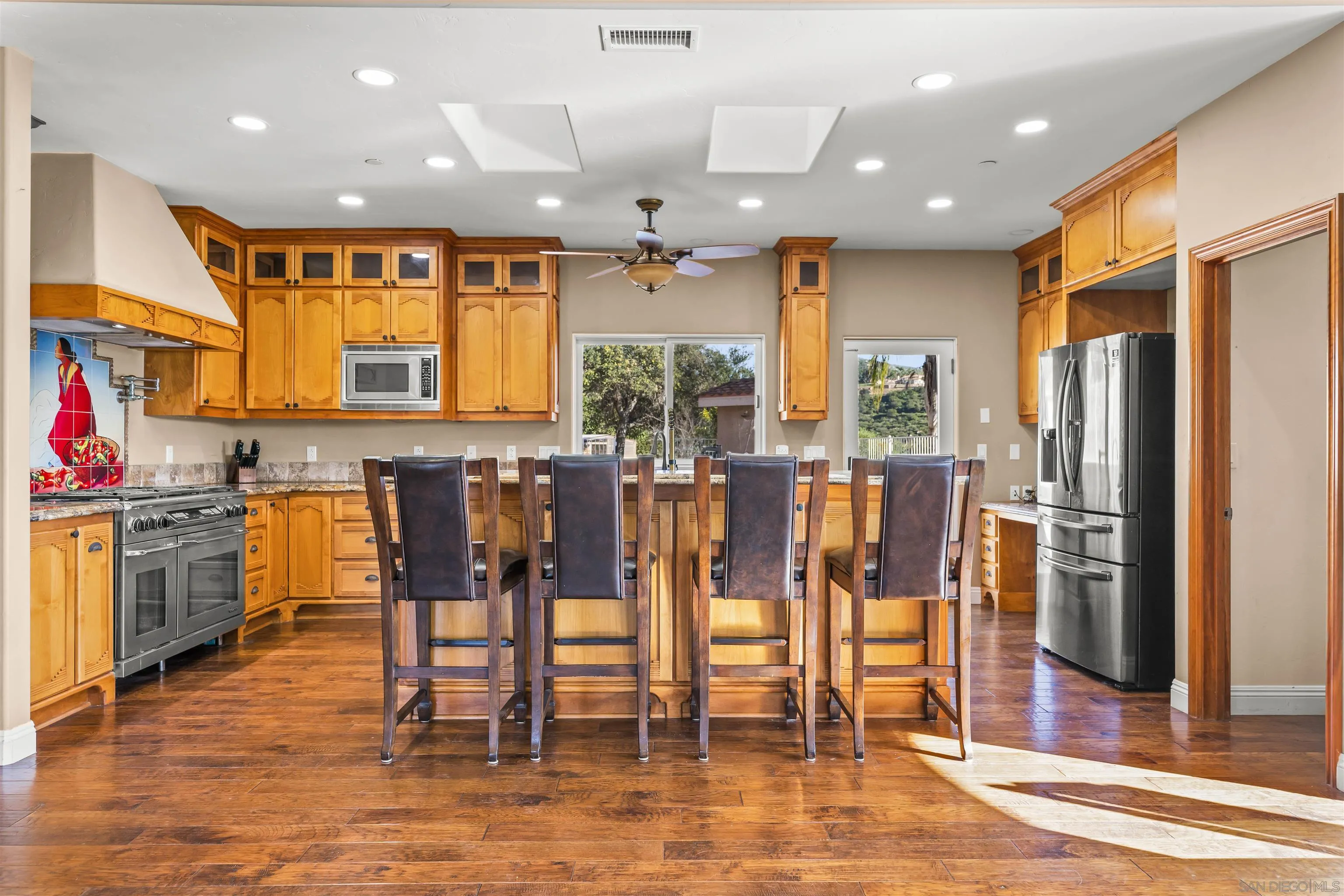 16951 Old Coach Road Poway, CA 92064 - Photo 12 of 70 a kitchen with stainless steel appliances kitchen island granite countertop a refrigerator cabinets and chairs
