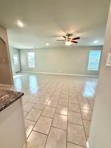 a view of an empty room and a ceiling fan kitchen view