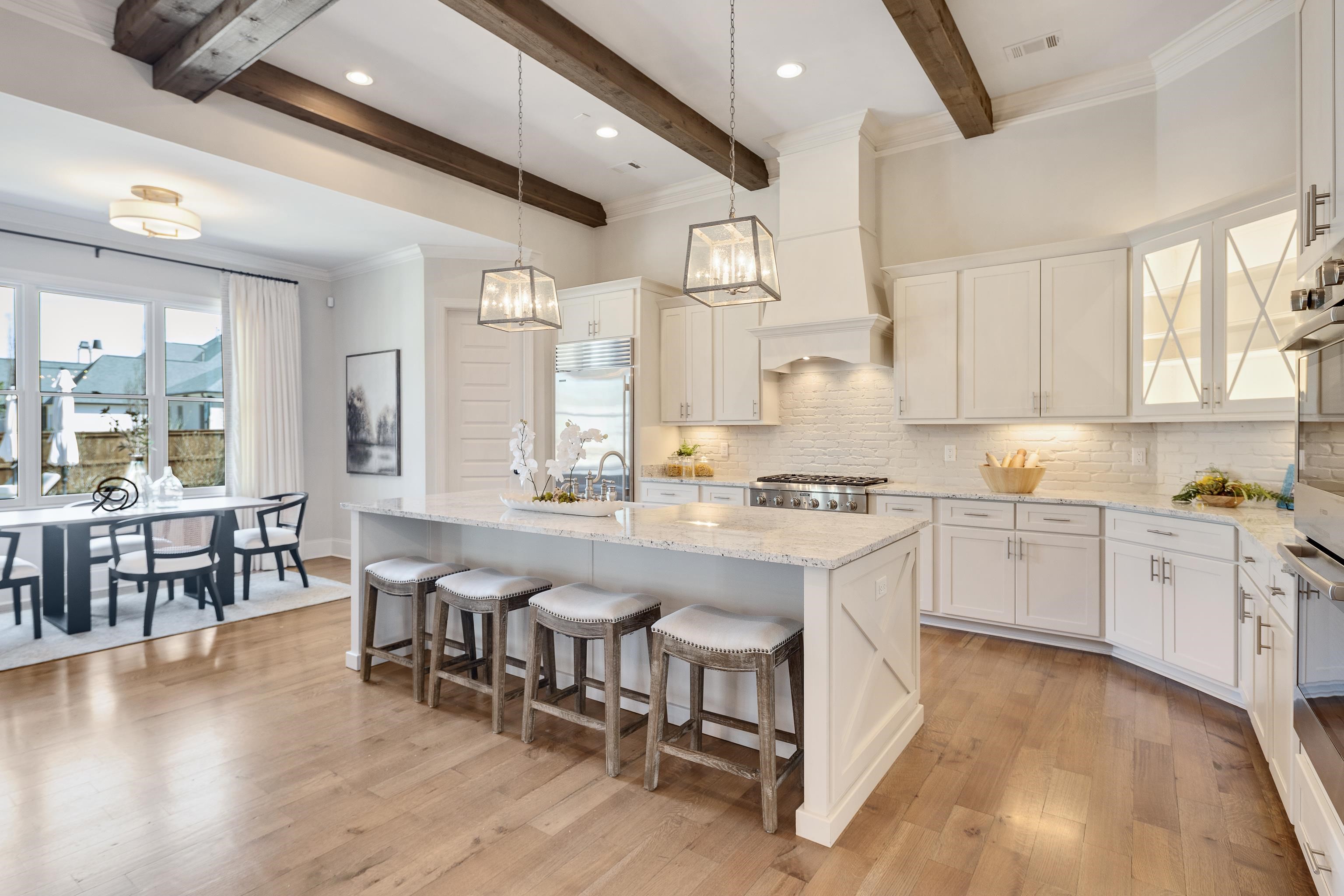 516 Lambs Brook Lane Collierville, TN 38017 - Photo 14 of 39 Kitchen featuring ornamental molding, a kitchen island with sink, light stone counters, a breakfast bar, and white cabinetry
