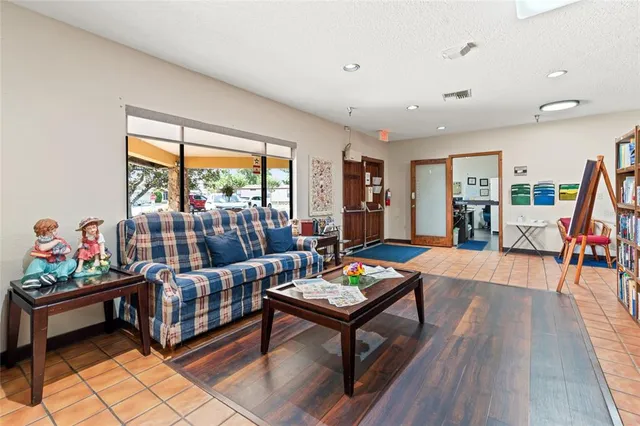 a living room with lots of furniture a clock on the table and a large window