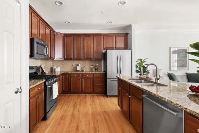 a kitchen with stainless steel appliances granite countertop a stove a sink dishwasher a refrigerator and a wooden cabinets