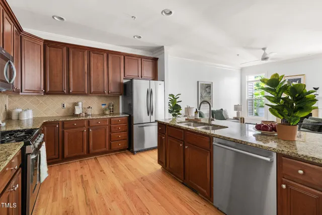 a kitchen with stainless steel appliances granite countertop a refrigerator a sink dishwasher a stove with wooden cabinets and floor