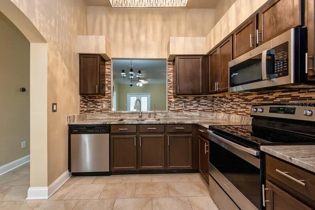 a kitchen with stainless steel appliances granite countertop a stove a sink and a microwave
