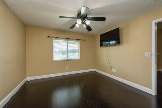 a view of empty room with wooden floor and fan