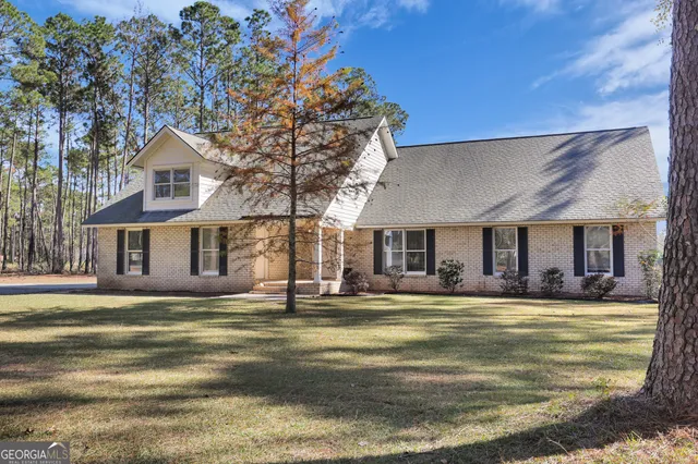 a view of a house with a big yard and large trees