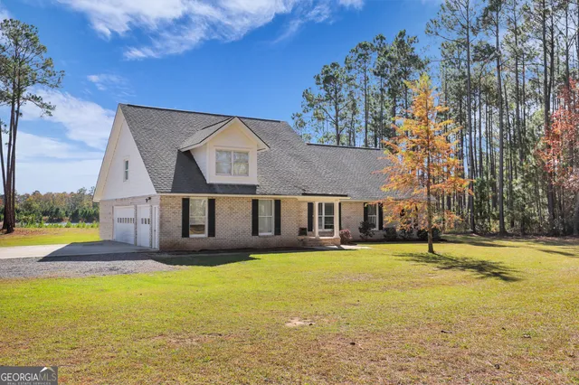 a front view of house with yard and trees in the background