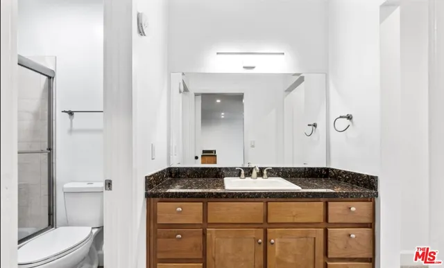 a bathroom with a granite countertop sink a toilet and a mirror