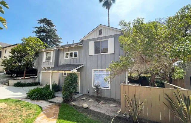 a front view of a house with a yard and tree