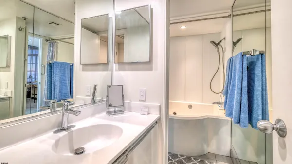 a bathroom with a granite countertop sink vanity mirror and shower