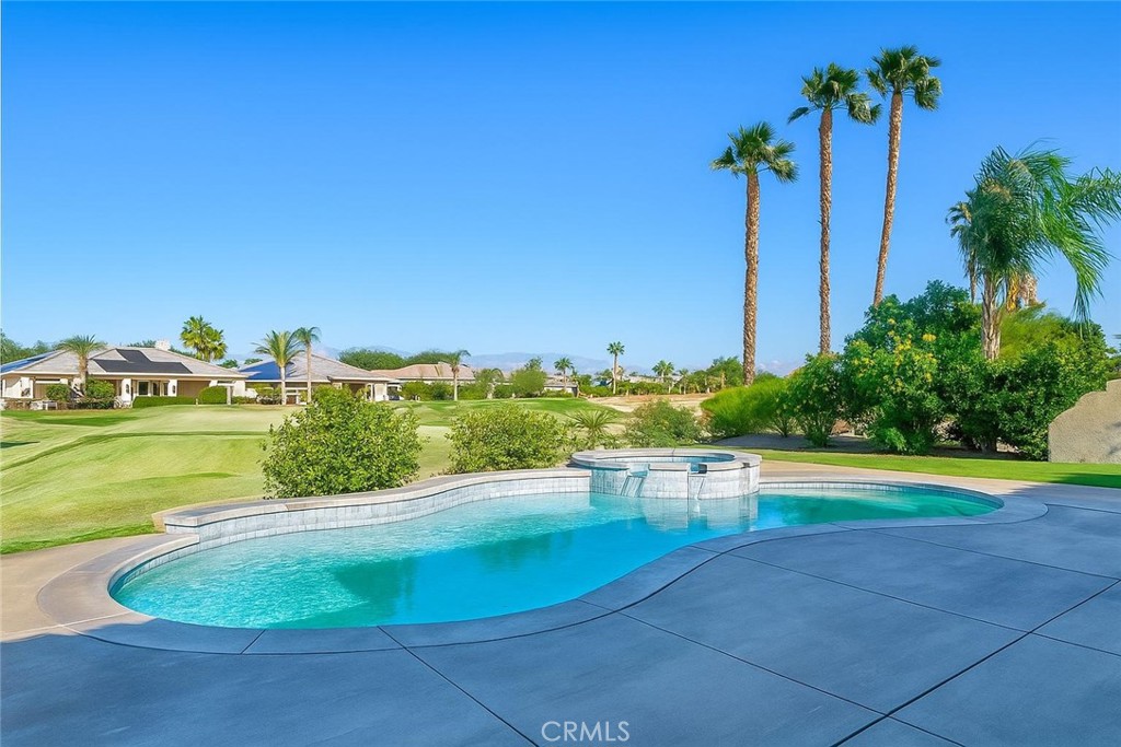 a view of a swimming pool with a yard and palm trees