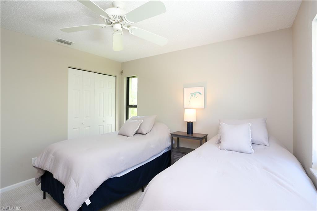 5733 Deauville Circle, Unit G308 Naples, FL 34112 - Photo 11 of 50 a bedroom with two beds and a chandelier