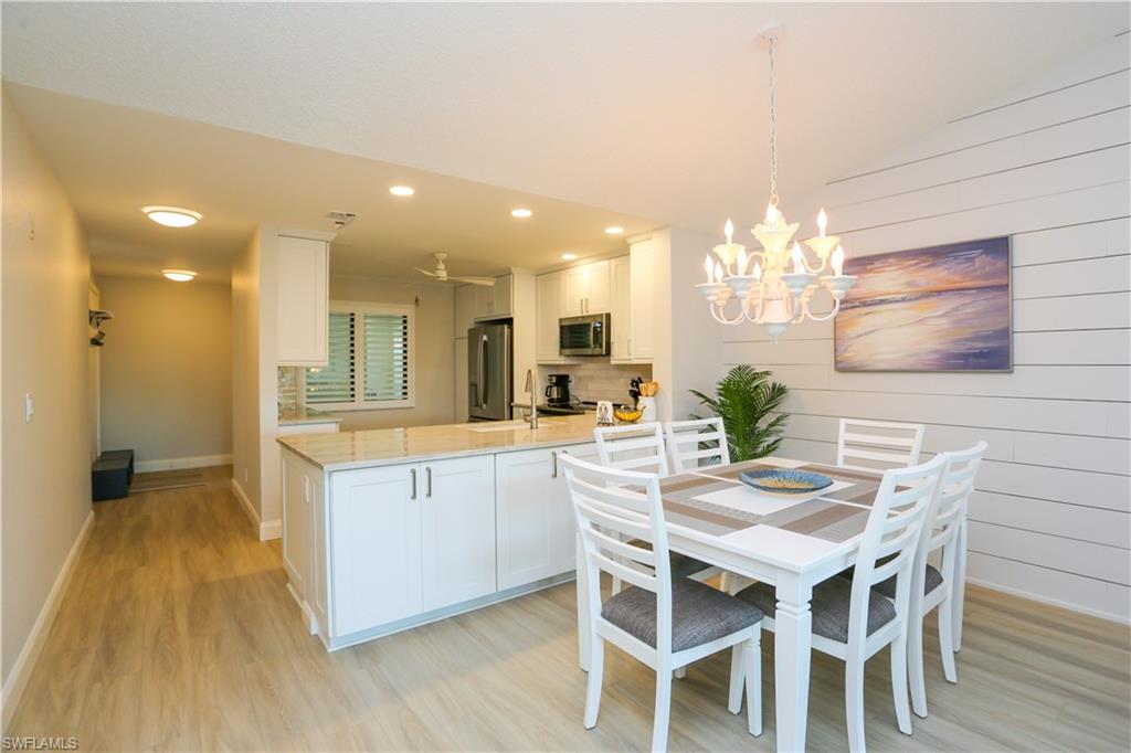 5733 Deauville Circle, Unit G308 Naples, FL 34112 - Photo 17 of 50 a kitchen with a dining table chairs and wooden floor