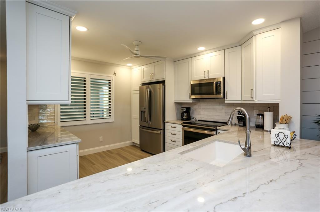 5733 Deauville Circle, Unit G308 Naples, FL 34112 - Photo 30 of 50 a kitchen with granite countertop a refrigerator stove and sink
