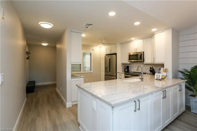 a kitchen with kitchen island a sink appliances and cabinets