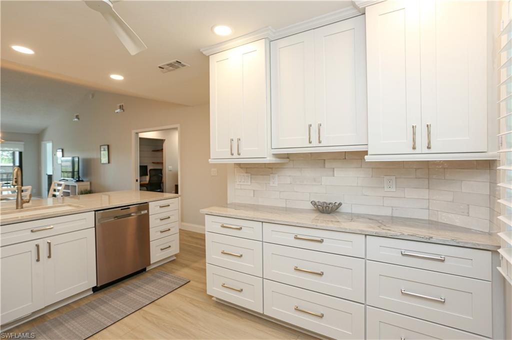 5733 Deauville Circle, Unit G308 Naples, FL 34112 - Photo 37 of 50 a kitchen with granite countertop white cabinets and white stainless steel appliances