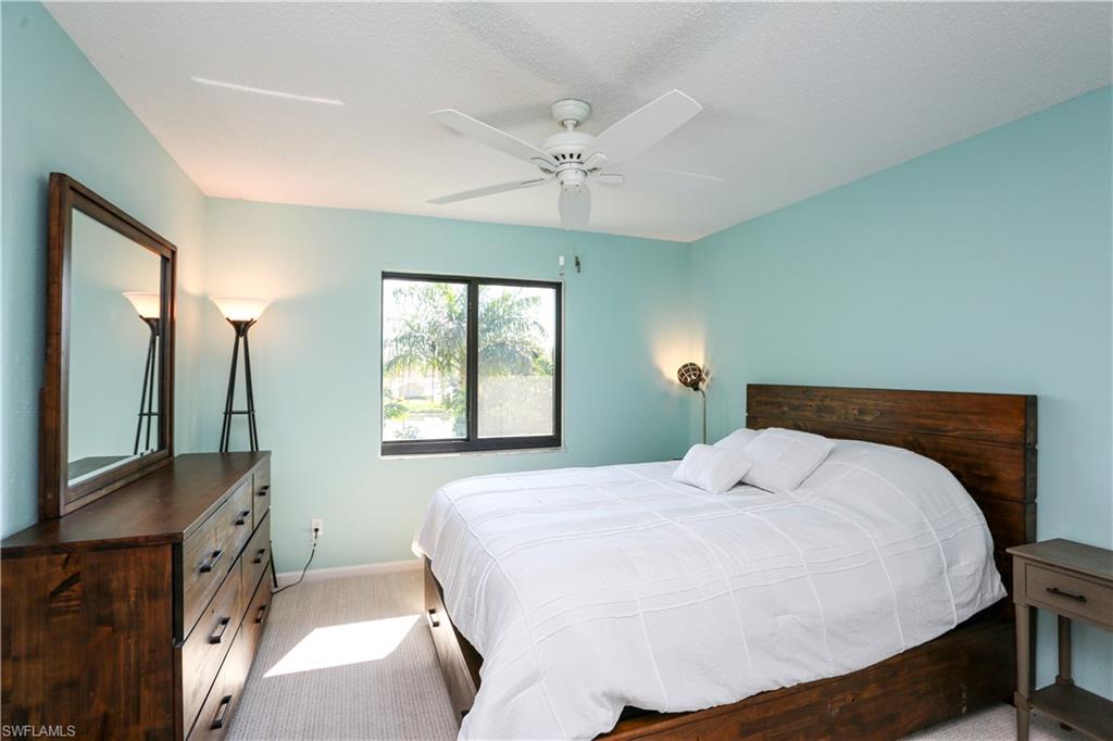 5733 Deauville Circle, Unit G308 Naples, FL 34112 - Photo 40 of 50 a bedroom with a bed a chandelier and a flat tv