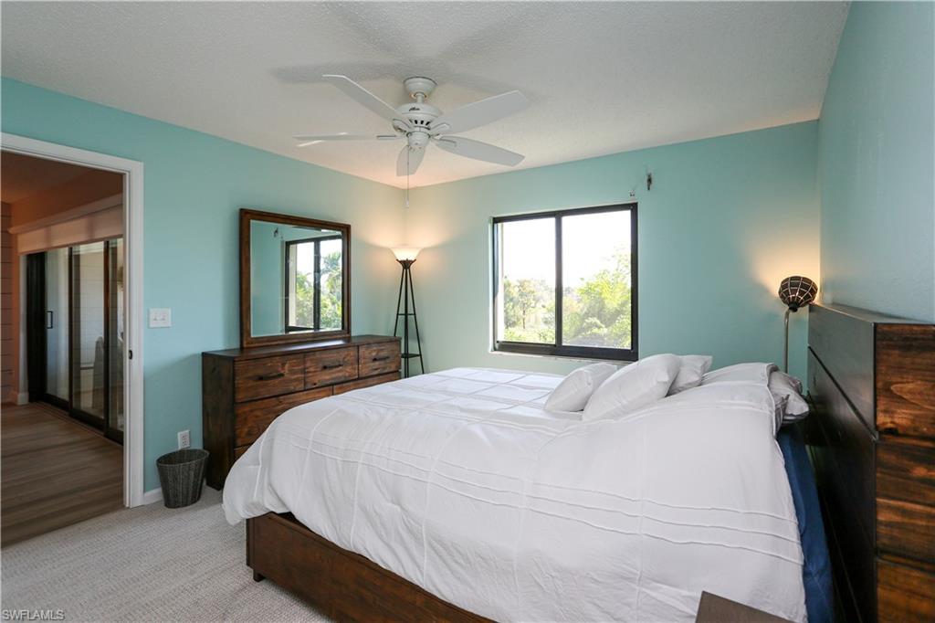 5733 Deauville Circle, Unit G308 Naples, FL 34112 - Photo 41 of 50 a bedroom with a bed and a chandelier