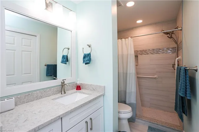 a bathroom with a granite countertop sink toilet and shower