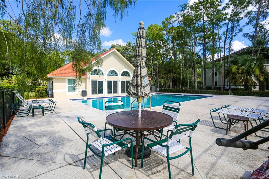 5733 Deauville Circle, Unit G308 Naples, FL 34112 - Photo 49 of 50 a view of a patio with table and chairs and potted plants