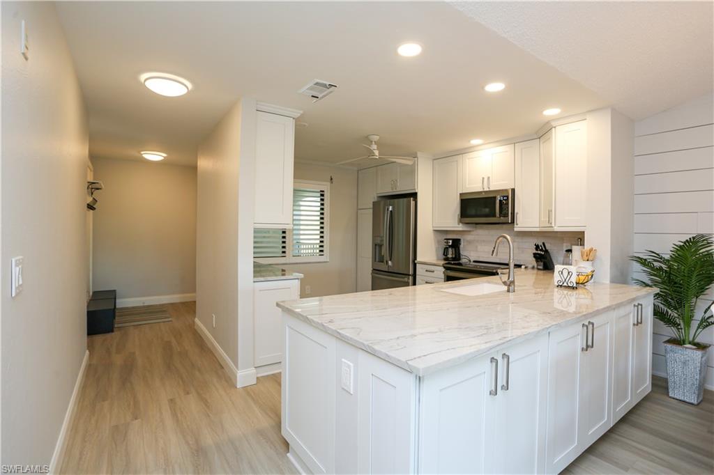 5733 Deauville Circle, Unit G308 Naples, FL 34112 - Photo 7 of 50 a kitchen with sink a refrigerator and microwave