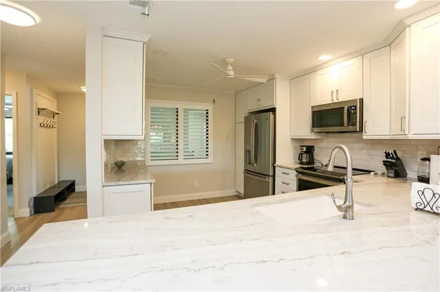 a kitchen with stainless steel appliances kitchen island granite countertop a refrigerator and a sink
