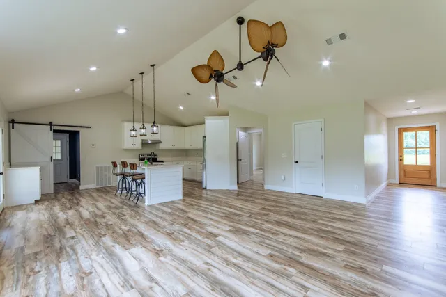 a view of a room with kitchen island stainless steel appliances wooden floor and window