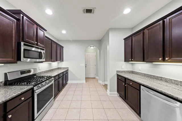 a kitchen with stainless steel appliances granite countertop a stove top oven a refrigerator and a sink
