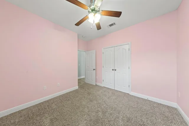 an empty room with closet and a chandelier fan