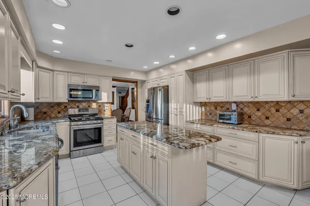 a kitchen with granite countertop a sink stove cabinets and refrigerator