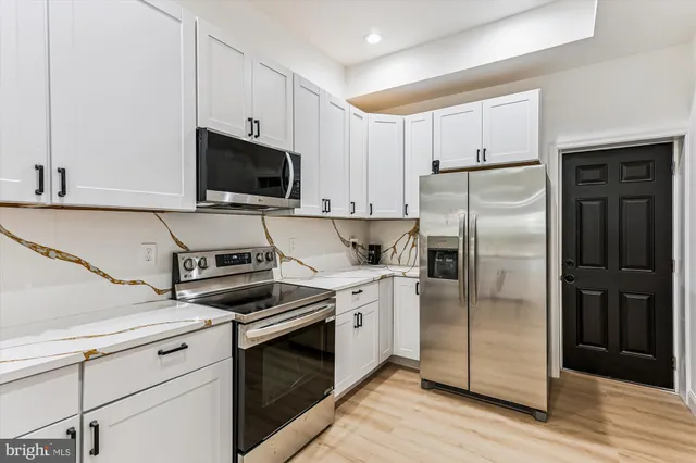 a kitchen with cabinets stainless steel appliances and wooden floor