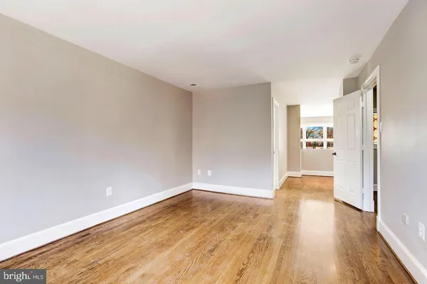 a view of a big room with wooden floor and windows