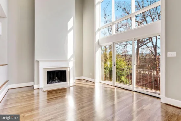 a view of an empty room with wooden floor fireplace and a window