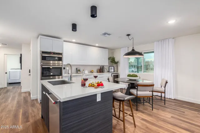 a kitchen with a stove a refrigerator and a dining table with wooden floor