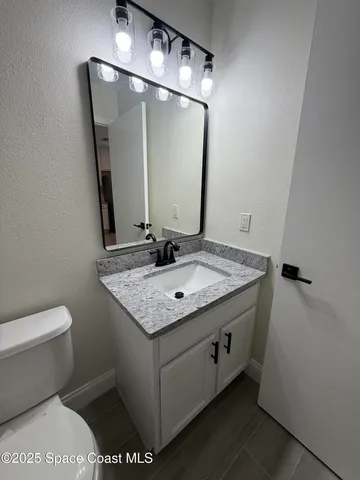 a bathroom with a granite countertop sink a toilet and a mirror